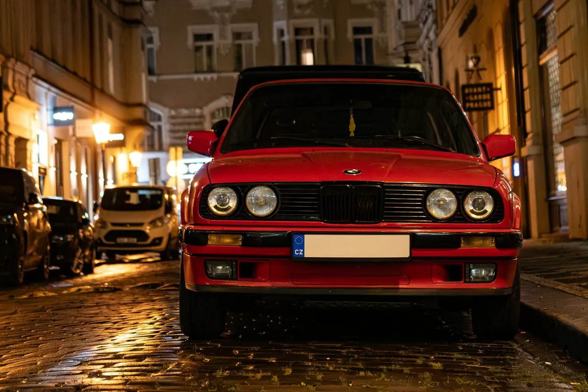 Roter BMW-Klassiker nachts auf nassem Kopfsteinpflaster in der Altstadt