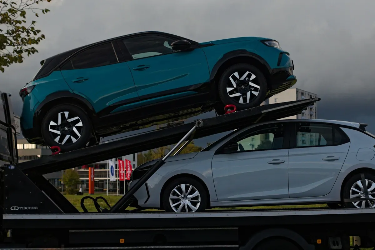 Zwei Autos auf einem Autotransporter vor dunklem Himmel