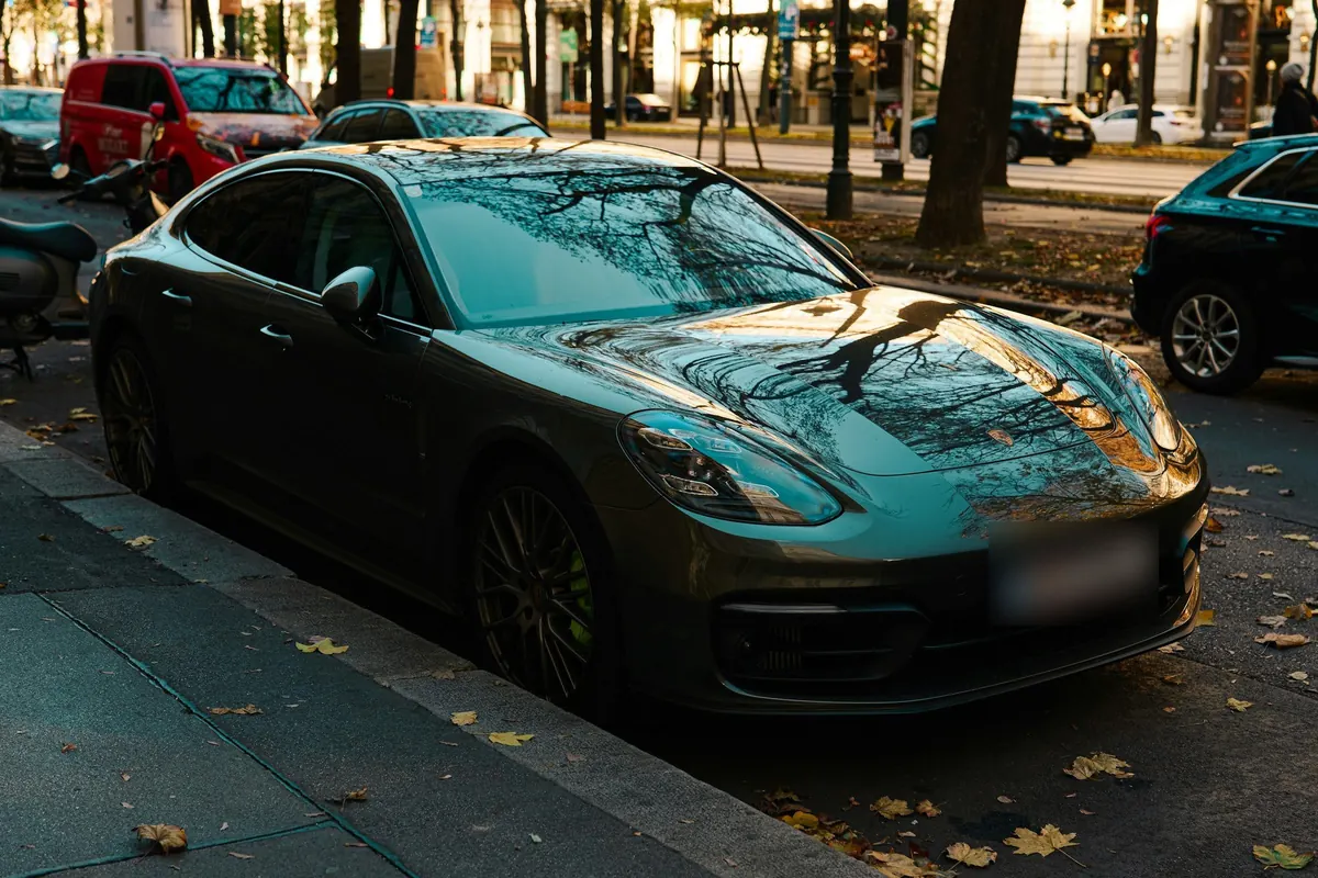 Dunkle Sportlimousine am Straßenrand in Wien im Herbstlaub
