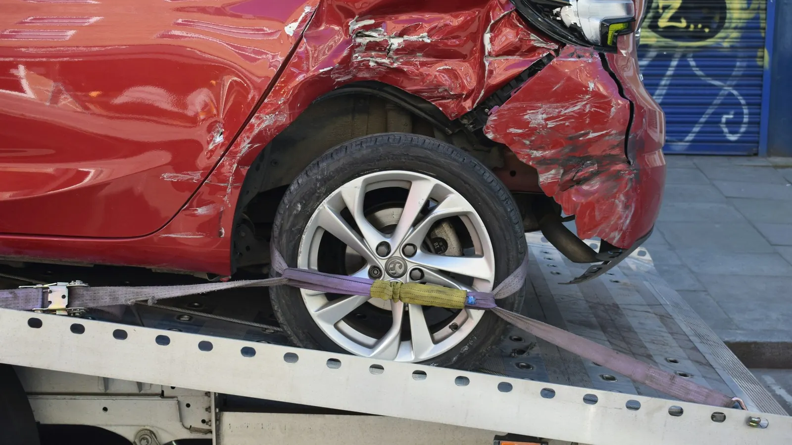 Rotes Auto mit Unfallschaden, auf einem Abschleppwagen gesichert